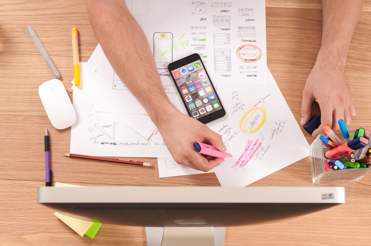 Mobile app screens being sketched beside a smartphone